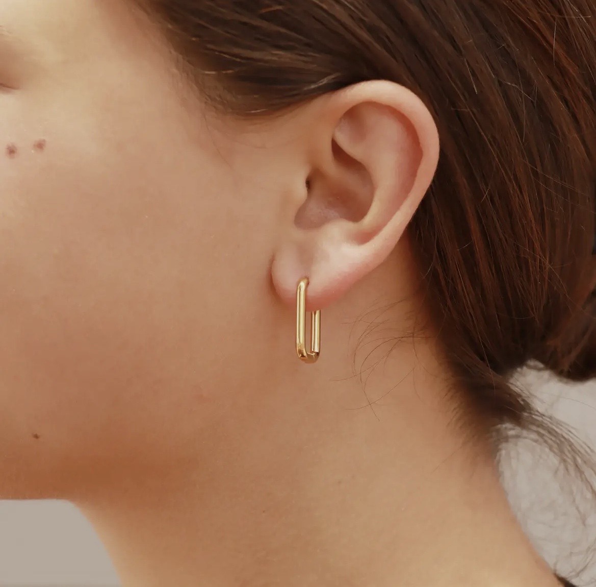 Close-up of a person wearing a gold hoop earring.