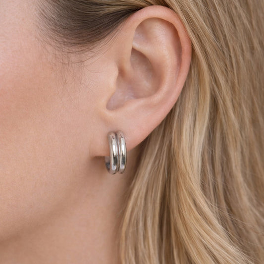 Close-up of a person wearing a silver hoop earring with blonde hair.