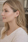 Woman wearing gold earrings with a neutral background