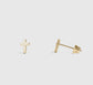 Gold cross-shaped earring on a light gray background