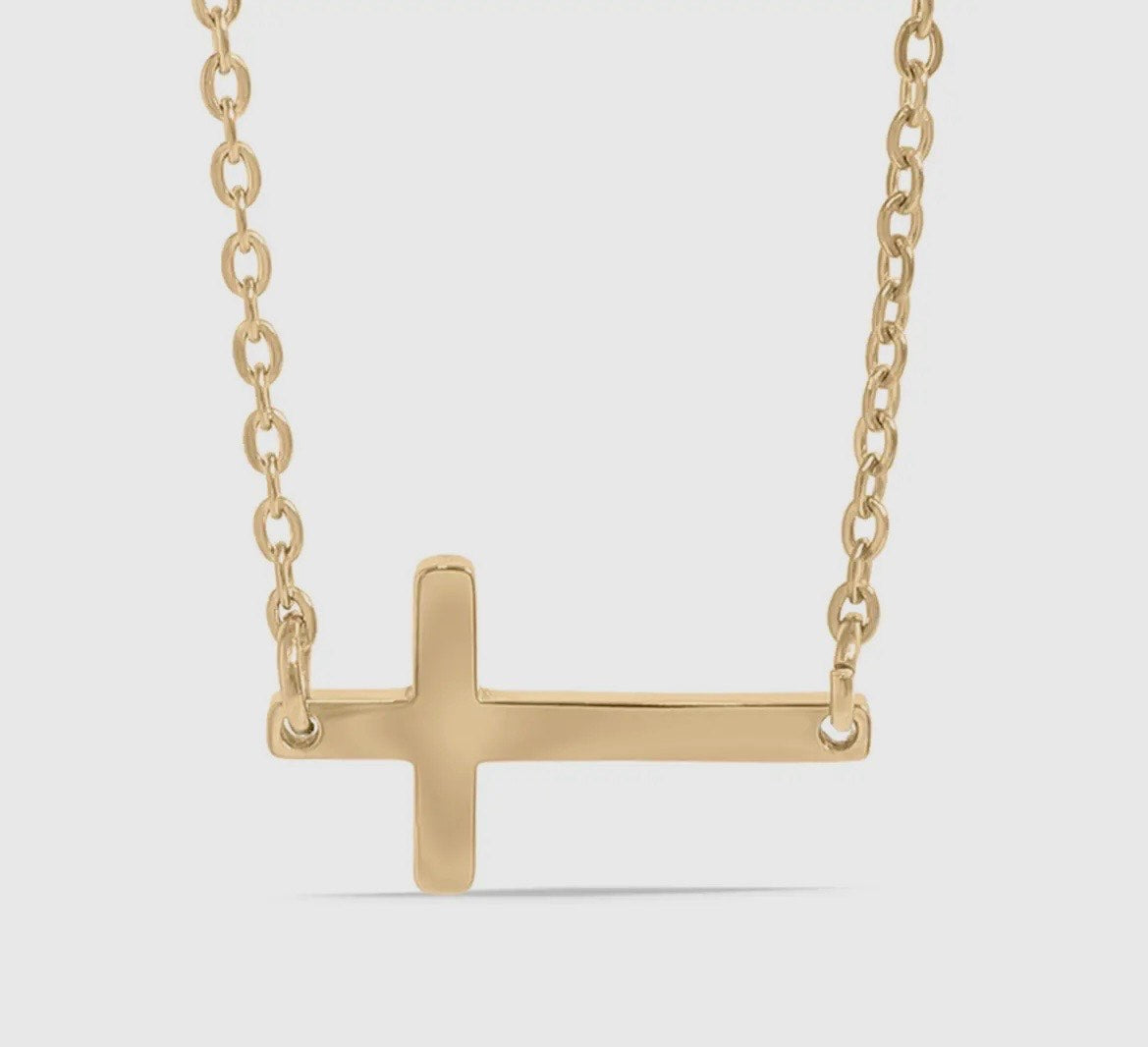 Gold cross necklace on a light gray background