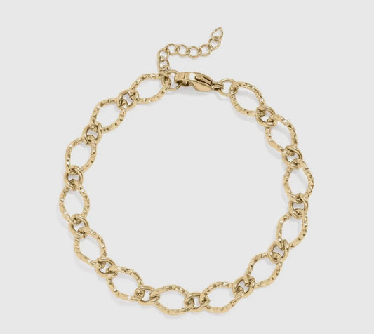 Gold chain bracelet on a light gray background