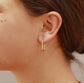 Close-up of a person wearing a gold hoop earring.