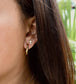 Close-up of an ear wearing a gold hoop earring with a small cross detail.