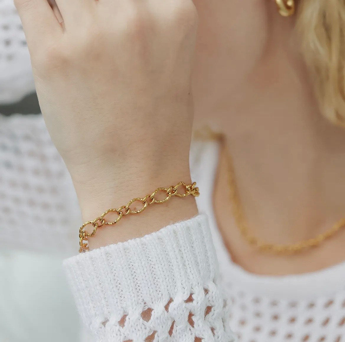 Gold chain bracelet on a wrist with a blurred background