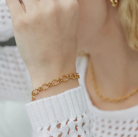 Gold chain bracelet on a wrist with a blurred background