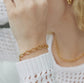 Gold chain bracelet on a wrist with a blurred background